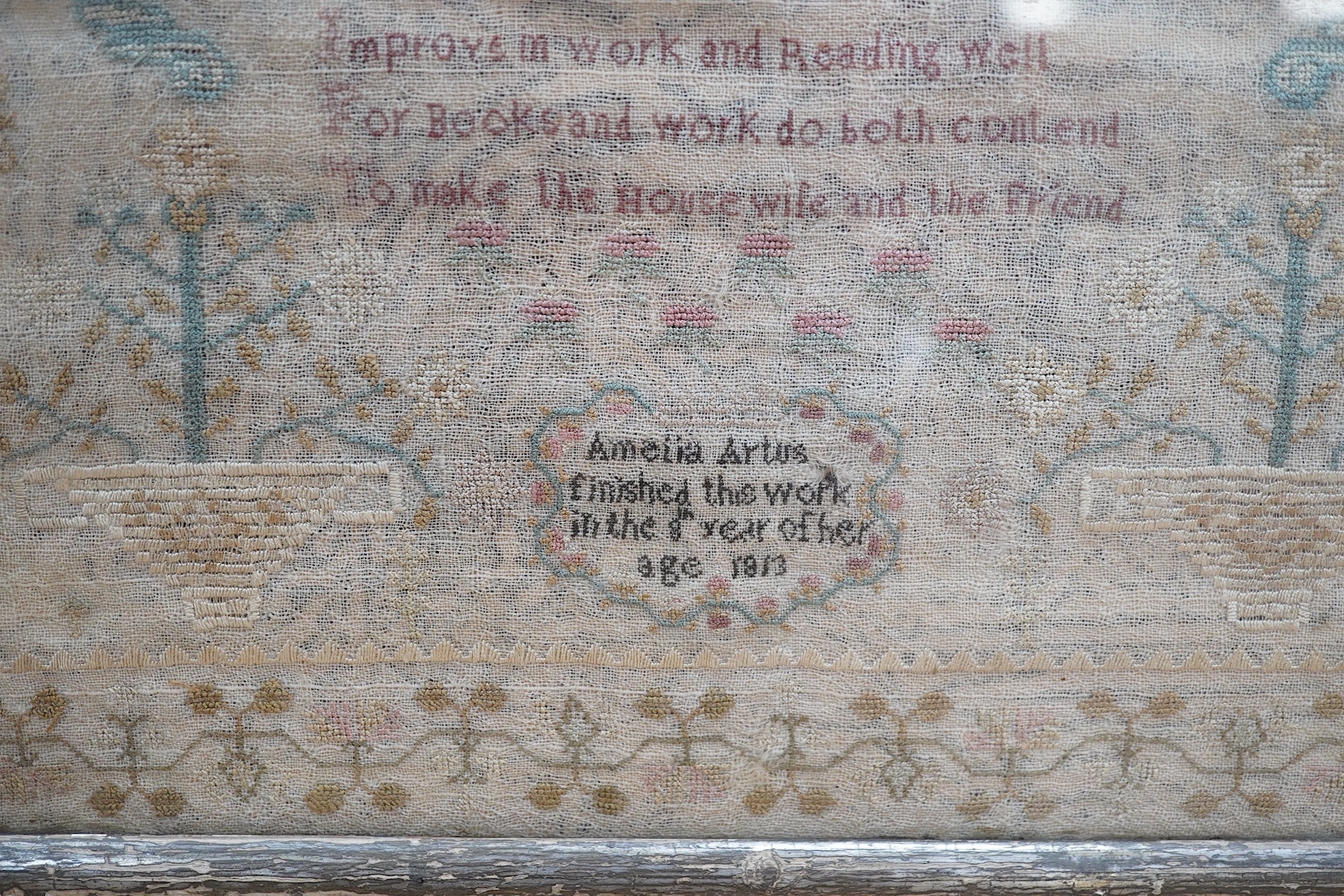 A gilt framed finely worked Regency gauze sampler, by Amelia Artus, aged 8 years, dated 1813, worked on fine gauze with coloured silk threads, with a large central panel having a long verse, two motifs of cornucopia, pot